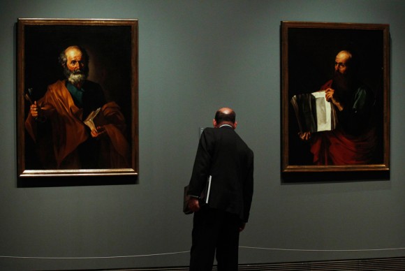 A man stands between the paintings San Pedro Saint Peter 580x388 Prado Museum Presents an Exhibition of a Previously Unknown Period in Riberas Career