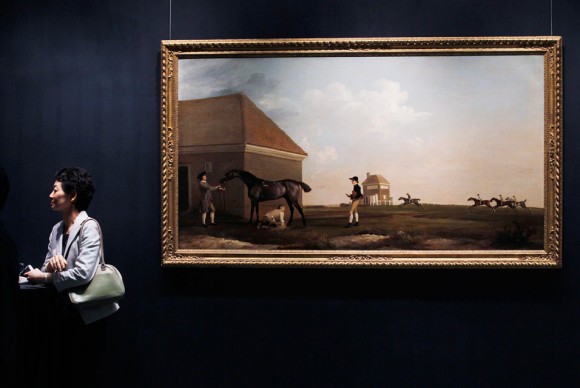 A visitor stands next to the painting Gimcrack on Newmarket Heath with a Trainer a Stable Lad and a Jockey 580x388 Christies Previews Lots from Impressionist and Modern Art Evening Sales in Hong Kong