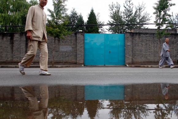 Chinese men dressed like monks walk past the home of activist artist Ai Weiwei in Beijing 580x388 Outspoken Artist Ai Weiweis Design Firm Told It Has Not Paid Corporate Taxes