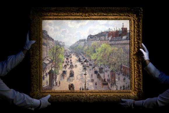 In a file picture taken on January 29 2014 Sothebys employees hold up Danish French artist Camille Pissarros Le Boulevard Montmartre matinee de printemps  580x388 Camille Pissarro, Pierre Bonnard, and Pablo Picasso records broken at Sothebys London